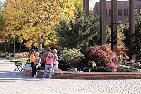 Four students sit outside by the clocktower